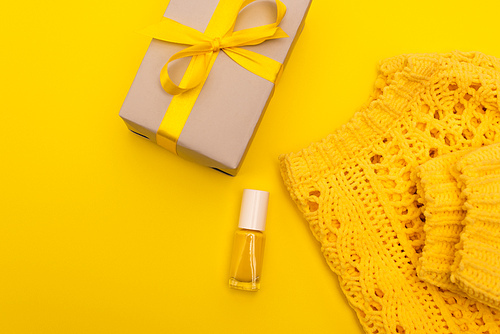 top view of nail polish near wrapped present and jumper isolated on yellow