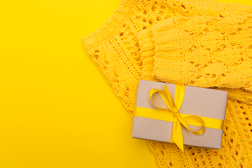 top view of wrapped present near knitted jumper isolated on yellow