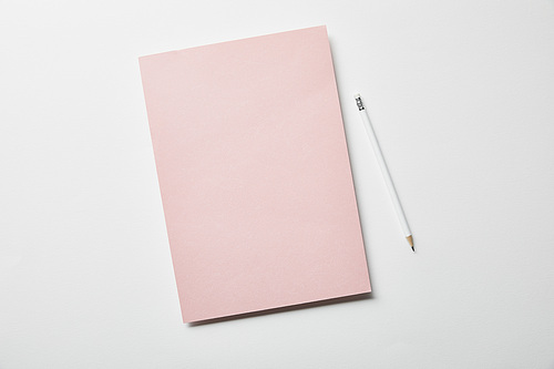 top view of pink paper and pencil on white surface