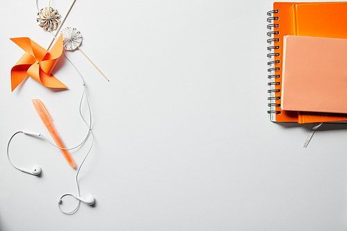 top view of orange notebooks, decoration objects and earphones on white surface
