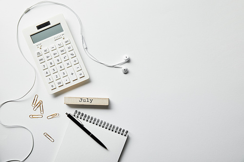 top view of stationery, calculator, earphones and notebook with pen on white surface