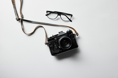 top view of photo camera and glasses on white surface