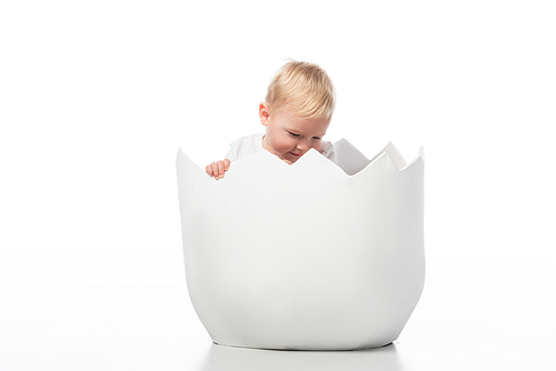 Cute child looking down inside eggshell on white background