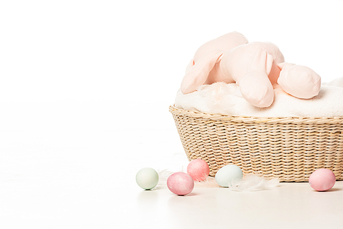 bunny on top of blanket in basket next to . eggs on white background