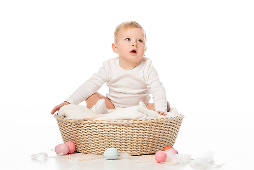 kid with open mouth sitting on blanket in basket with . eggs around on white background
