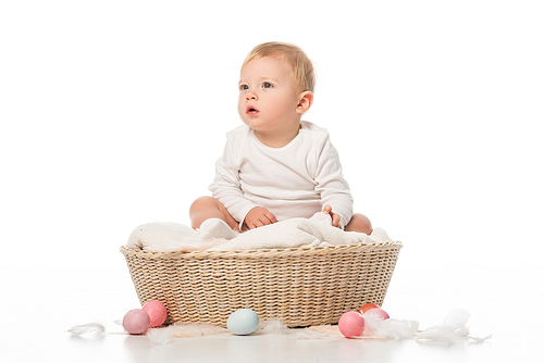 child with open mouth sitting on blanket in basket with . eggs around on white background