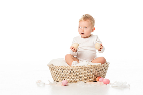 kid holding . eggs, looking away with open mouth, sitting in basket on white background