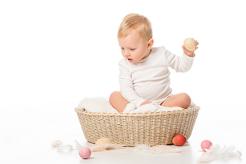 child holding . egg, looking down with open mouth in basket on white background