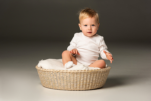 Cute child , sitting on blanket in basket on black background