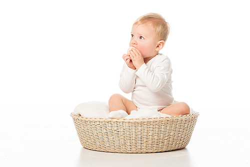 cute boy taking . egg to mouth by clenched hands in basket on white background