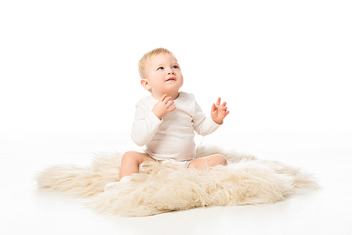 Cute child looking up and sitting on fur on white background