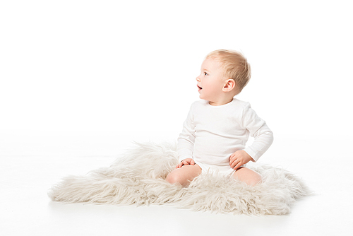 Cute kid looking away with open mouth and sitting on fur on white background