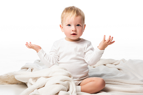 Cute child spreading hands to sides and sitting on blanket on white background