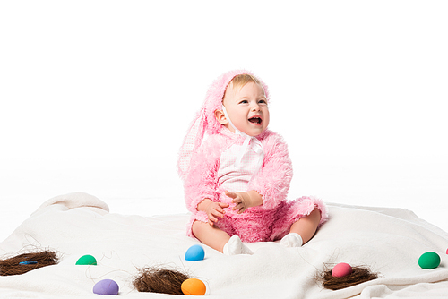 Kid wearing rabbit costume, shouting out on blanket with colorful decoration isolated on white