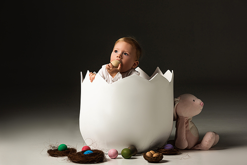 child taking . egg to mouth by clenched hands inside eggshell on black background