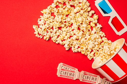 Top view of popcorn, cinema tickets and 3d glasses on red background