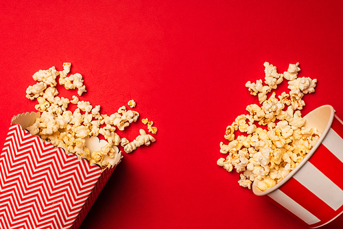 Top view of buckets with delicious popcorn on red background