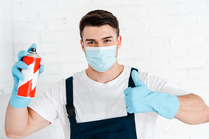 exterminator in latex gloves holding toxic spray can and showing thumb up