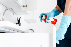 cropped view of exterminator in latex gloves holding spray can near kitchen cabinet