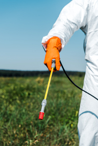 cropped view of exterminator in orange latex glove and white uniform holding spray outside