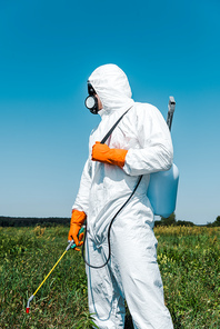 exterminator in white uniform and latex gloves holding spray