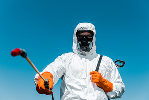 selective focus of exterminator in uniform and latex gloves holding spray outside