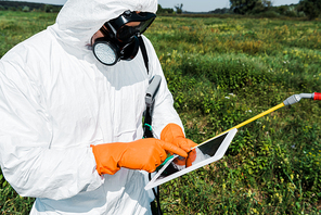 exterminator in protective mask and uniform pointing with finger at laptop