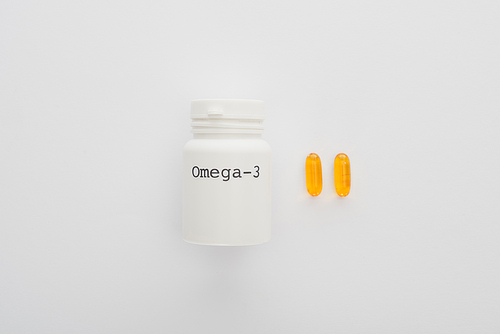 Top view of container with omega-3 lettering and yellow capsules on white background