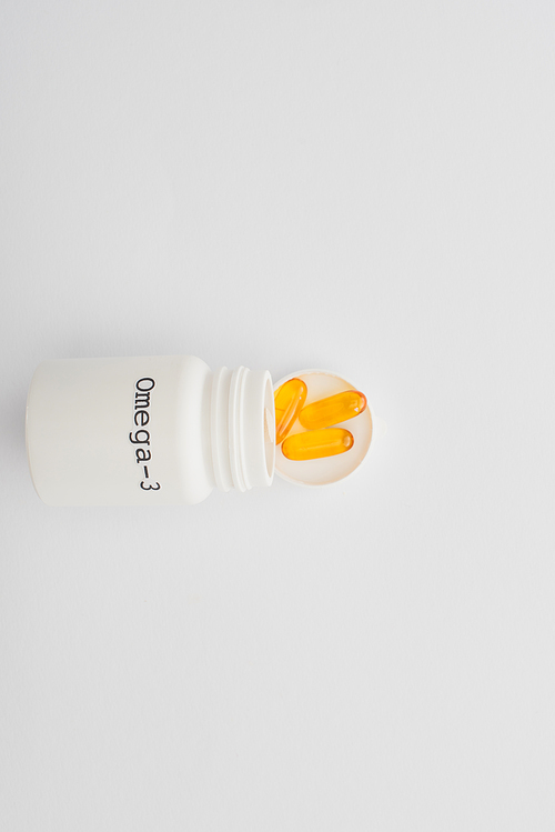 Top view of opened container with omega-3 capsules on white background