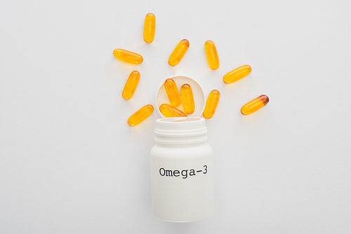 Top view of opened container with omega-3 yellow capsules on white background
