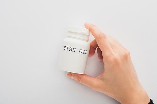 Cropped view of woman holding container with fish oil lettering on white background