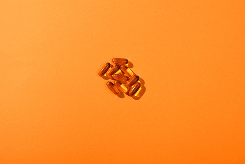 Top view of brown capsules on orange background