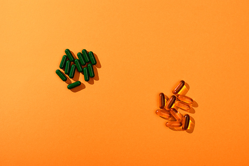 Top view of brown and green capsules on orange