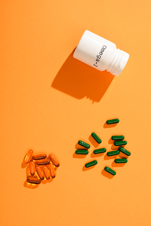 Top view of container with omega-3 lettering and capsules on orange