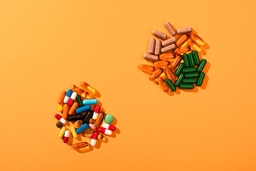 Top view of colorful pills and capsules on orange background