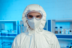scientist in hazmat suit, medical mask and goggles looking at camera