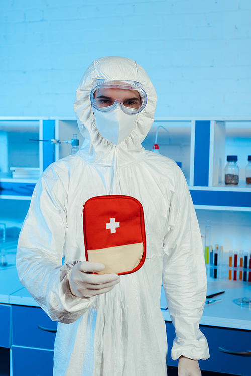scientist in hazmat suit and goggles holding first aid kit