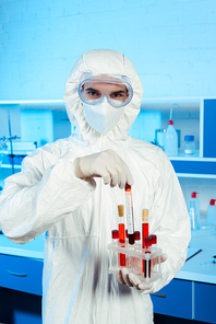 scientist in hazmat suit and latex gloves holding test tube with lettering