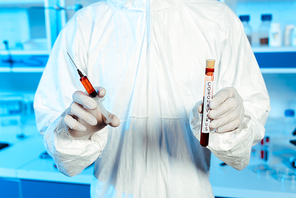 cropped view of scientist in latex gloves holding syringe and test tube with coronavirus lettering