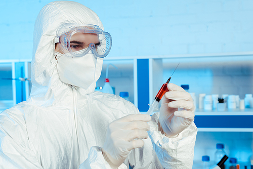 scientist in latex gloves holding syringe with vaccine