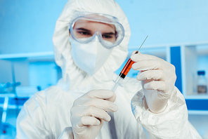 selective focus of scientist in latex gloves holding syringe with vaccine