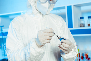 cropped view of scientist in latex gloves holding syringe and bottle with vaccine