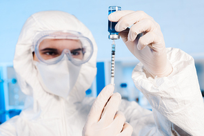 selective focus of scientist holding syringe and bottle with vaccine