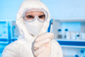 selective focus of syringe with vaccine in hand of scientist
