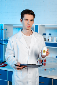 handsome scientist holding clipboard and bottle with toxic symbol