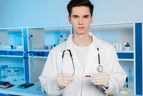 handsome scientist in latex gloves holding digital thermometer