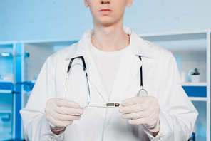 cropped view of scientist in latex gloves holding digital thermometer