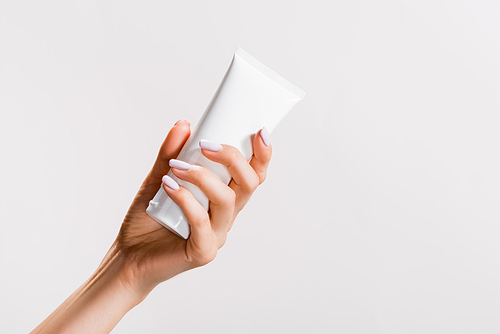 cropped view of woman holding tube of hand cream isolated on grey