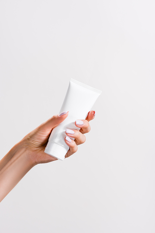 cropped view of woman holding tube of hand cream isolated on grey