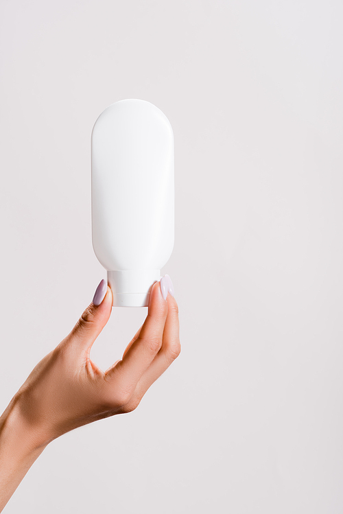 cropped view of woman holding tube of hand lotion isolated on grey